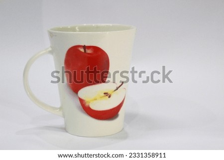 Hand holding a white glass with an apple picture on a white background