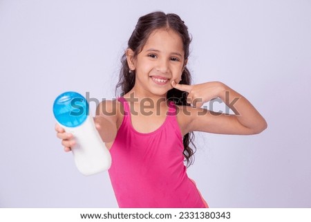 Adorable little girl in a pink swimsuit holding a sunscreen with blank space for text. Holiday and summer care
