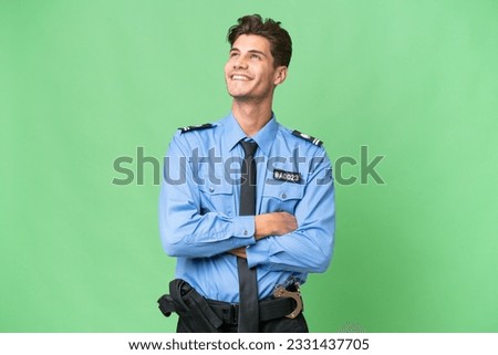Young police man over isolated background looking up while smiling