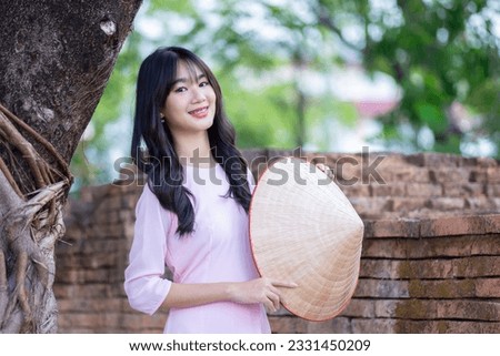 Portrait women in pink ao dai Vietnam and holding straw hats, The Ao dai ( long-dress Vietnamese) is traditional costume of Vietnamese woman. Asian Vietnamese women in traditional costumes