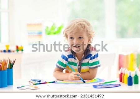 Kids paint. Child painting in white sunny study room. Little boy drawing rainbow. School kid doing art homework. Arts and crafts for kids. Paint on children hands. Creative little artist at work. Royalty-Free Stock Photo #2331451499