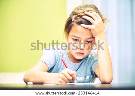 Little girl is doing her homework for elementary school.