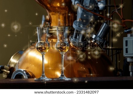 Liqueur glasses with golden christmas stars in front of a gin distiller.