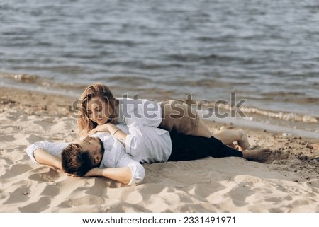 Guy and girl run barefoot on wet beach near sea in summer