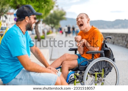 A disabled person in a wheelchair with a friend on summer vacation having fun laughing a lot Royalty-Free Stock Photo #2331518057