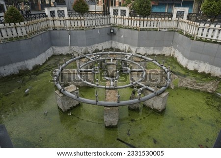 photo of the steel water pipe track structure in the ditch. form a circle, above the dirty green water, in java indonesia asia. need to be cleaned, the flow is more optimal and beautiful to look at