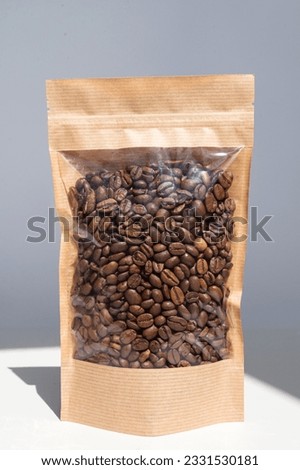 Brown kraft paper bag with coffee beans for viewing with a highlighted shadow on a white background. Layout of the packaging template for food and essential goods Royalty-Free Stock Photo #2331530181