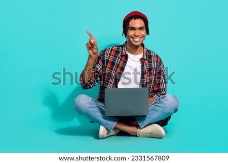 Full body photo of handsome guy it floor use netbook indicate finger empty space promo isolated on teal color background