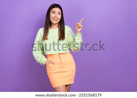 Photo of positive dreamy girl dressed green sweatshirt looking showing finger empty space isolated violet color background