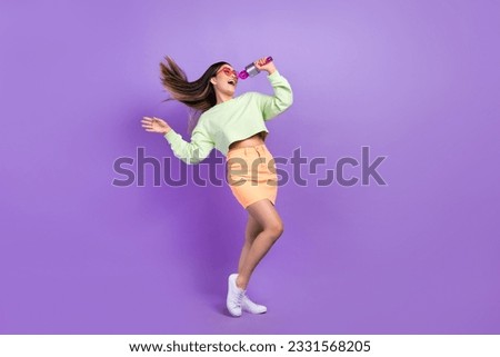 Full size photo of adorable pretty woman dressed green shirt stylish skirt sing in microphone on stage isolated on purple color background Royalty-Free Stock Photo #2331568205