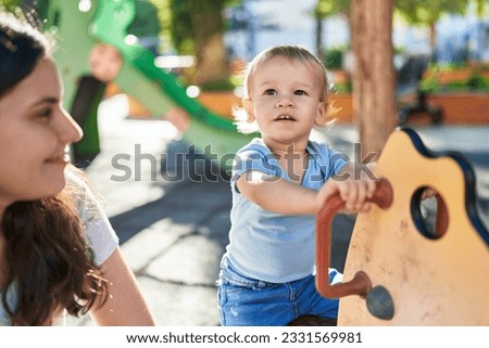 Mother and son playing on swing at park playground