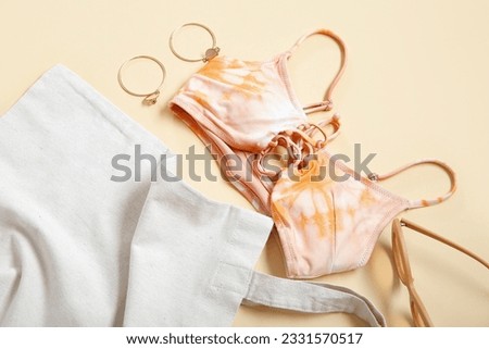 Stylish bikini top, bag, sunglasses and earrings on color background, closeup