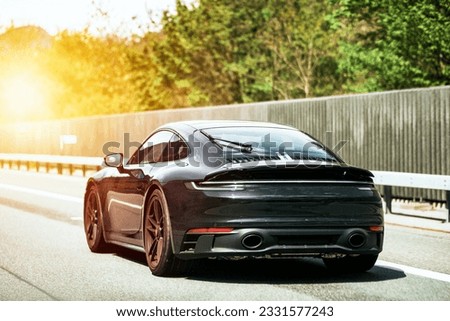 Sleek Black German Roadster. Brand New Luxury Carrera Sports Car on the Highway. Rear view of the 911 GTS sports car. Royalty-Free Stock Photo #2331577243