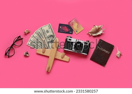 Composition with credit cards, money, wooden plane and photo camera on pink background
