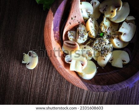 Top view of the Paris mushroom sliced with oregano in the rustic wooden bowl. Delicious champignon salad with oregano