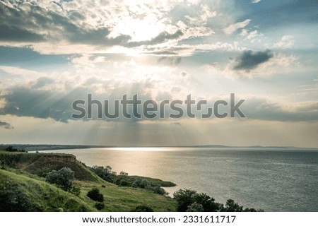 The sun breaking through the clouds with rays in a gloomy sky. Close-up. Change of weather at sea. Background. Space for text.
