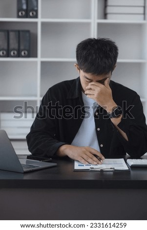 Asian businessman working online with laptop are stressed and tired from work sitting at desk in the office, feeling sick at work, stress from work.	