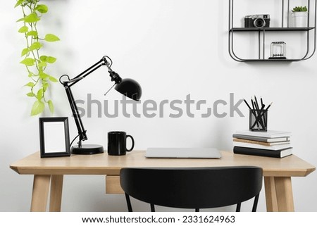 Cozy workspace with laptop, lamp and stationery on wooden desk at home Royalty-Free Stock Photo #2331624963