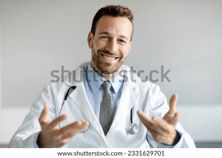 Head shot of cheerful male doctor in white uniform with stethoscope consulting patient online, speaking, looking at camera and gesturing, making video call Royalty-Free Stock Photo #2331629701