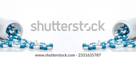 Blue-white antibiotic capsule pills spread out of plastic drug bottles. Antibiotic drug resistance. Prescription drugs. Healthcare and medicine. Pharmaceutical industry. Pharmacy product. Medication. Royalty-Free Stock Photo #2331635787