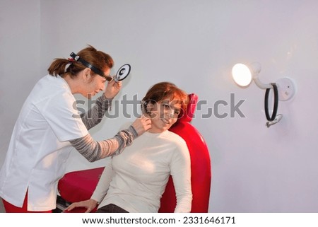 female doctor using a otoscope for an ear exam on an elderly patient