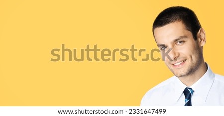 Portrait of happy smiling young brunette businessman in white shirt and blue tie, isolated over orange yellow colour background with copy space area. Confident business man at studio image.