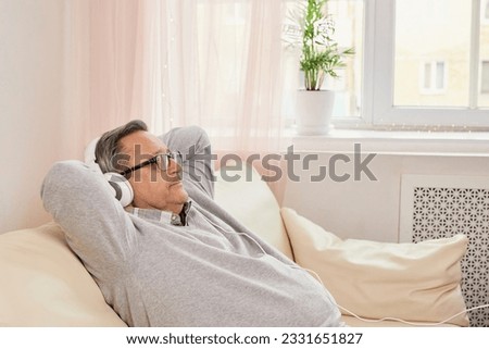Elderly man in headphones enjoying while listening to music. Senior resting in comfortable leisure setting, enjoying the serenity of healthy aging and retirement. Recreation, lifestyle, happiness