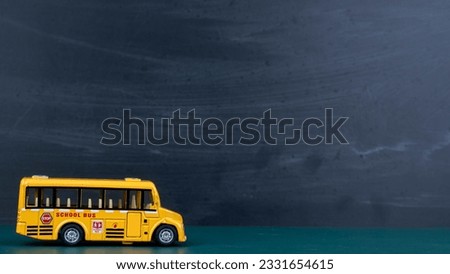 Yellow school bus miniature on book blackboard background.
Back to school concept.