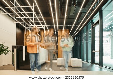 long exposure of businessmen with takeaway drinks walking and talking in lobby of modern coworking office with high tech interior, discussing and planning startup project during coffee break
