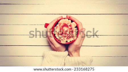 Female holding cup with flower.