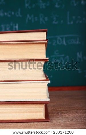 Books on wooden table on blackboard background