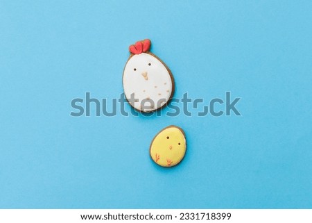 Easter gingerbread with icing, chicken, chick in egg form on pastel light blue backdround. Happy festive holiday, glazed cookie figures composition. Flat lay, top view, place for text, banner