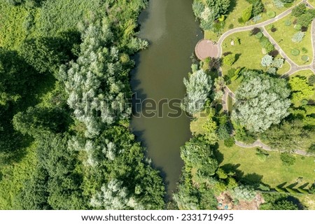 Drone-captured photo: Serene lake amidst green grass, clear sunny weather. Vibrant and tranquil summer landscape with reflective lake and natural beauty.