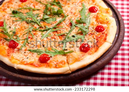Pizza with arugula and tomatoes on wooden board