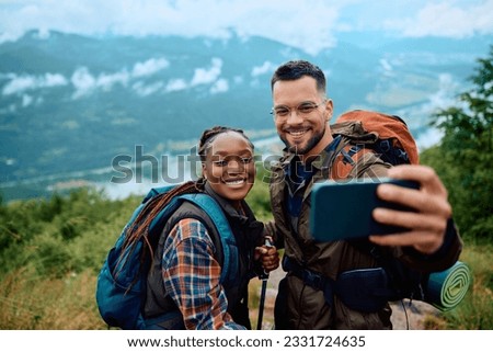 Happy hiker and his African American girlfriend taking selfie on top of a hill. Copy space. 