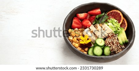 Healthy vegan lunch bowl. Avocado, quinoa, cucumber, red orange, chickpea, cheese, salad and strawberries on a white background. Top view. Panorama with copy space.