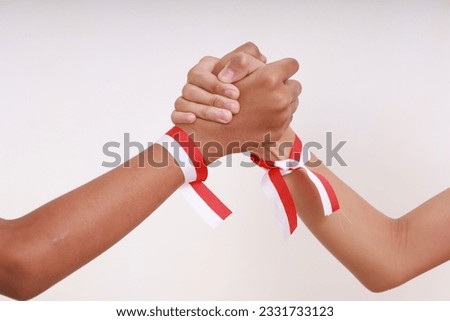 Kid's hands with red white ribbon holding each other. Indonesia independence day concept Royalty-Free Stock Photo #2331733123