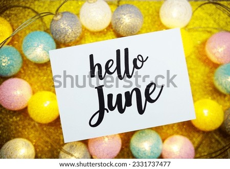 Hello June text on paper card with LED cotton balls decorate on yellow background