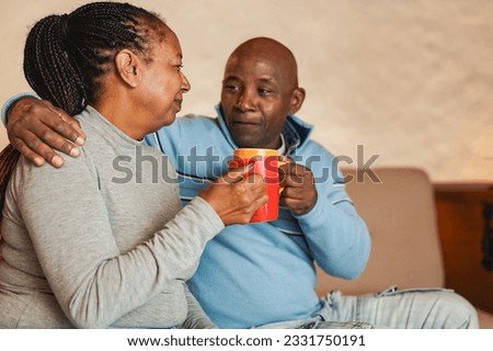 Happy african senior couple drinking together coffee at home
