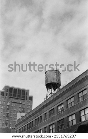 Black and white photo of a water tank on the roof of a building in New York City.