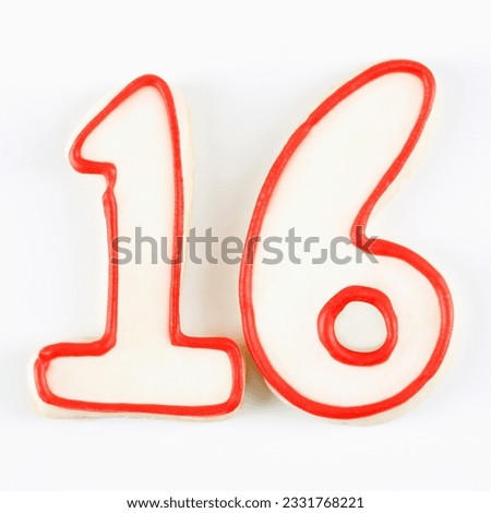 Sugar cookies in the shape of the number sixteen outlined in red icing.