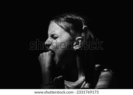 Lost childhood concept. Sad unhappy little child girl biting her fist as symbol of feeling of helplessness and despair. Black and white image.