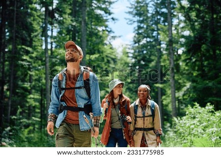 Group of young hikers walking through the woods. Focus is on man.  Royalty-Free Stock Photo #2331775985
