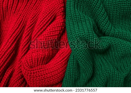 Red and green knitted sweater on white background top view. Texture of woolen cotton winter autumn cozy sweater, clothes. Knitted jumper, pullover, fashion
