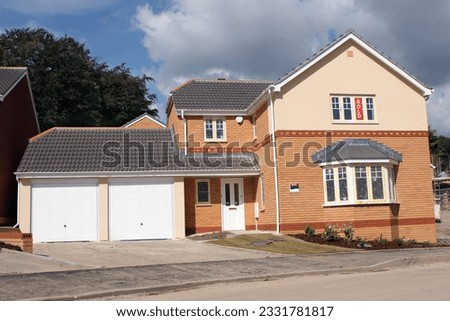 New detached brick house with a double garage with for sale signs.