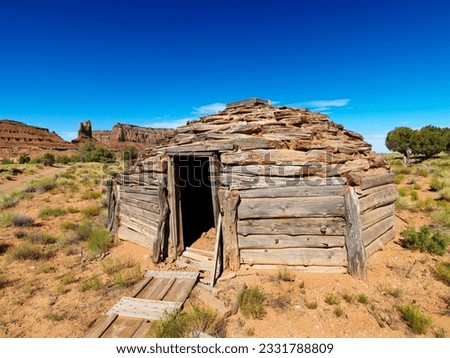 Desert landscape with rustic log cabin shelter.