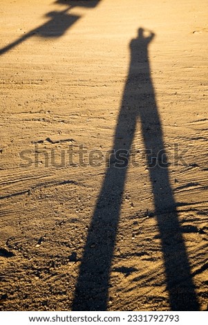 Shadow of man on dirt at sundown.