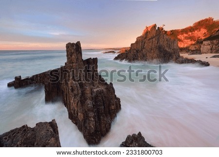 Ocean flows around volcanic sea stacks as first light strikes the landscape