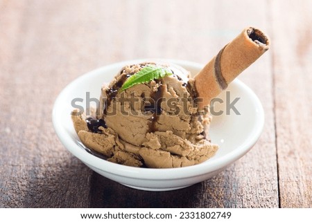 Plate of chocolate ice cream with syrup on dining table.