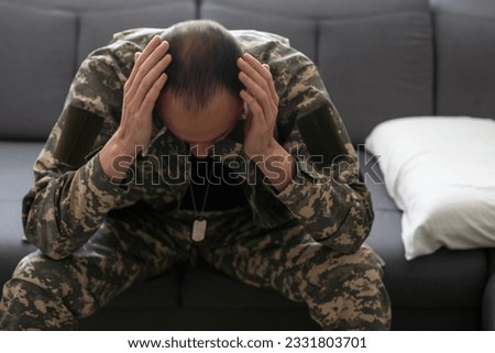 Closeup portrait of depressed military man covering his face with palms, sitting on couch at home and crying. Unhappy soldier visiting psychologist, suffering from posttraumatic stress, copy space Royalty-Free Stock Photo #2331803701